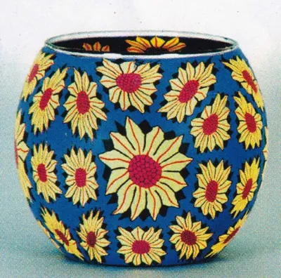 Ein Windlicht aus Fimo-Glas das mit mehreren Sonnenblumenmustern verziert ist.