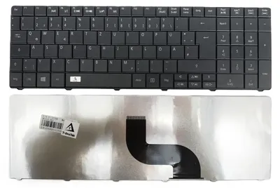 A black laptop keyboard and its silver backing with a ribbon cable.