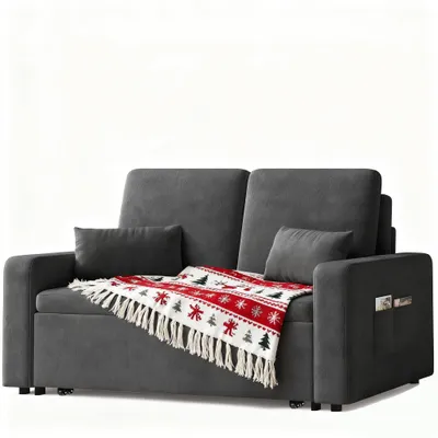 A dark gray sofa with a festive throw blanket draped over it, presented against a white background.