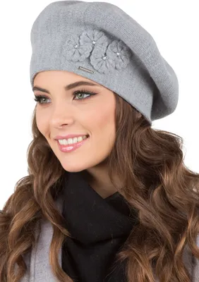A woman wearing a grey beret with floral embellishments and a black scarf.