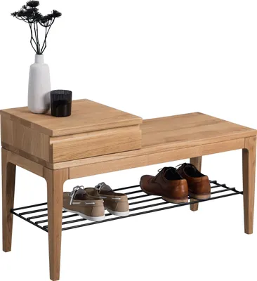 A wooden bench with a shoe rack underneath, featuring a drawer on one side and a vase with dried flowers and a candle on top.