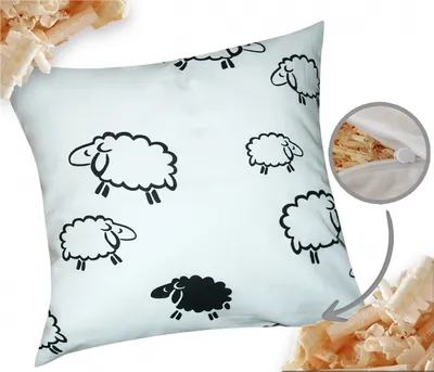 A white pillow with a pattern of black and white sheep, shown with a close-up of the zipper and filling.