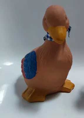 Niedliche Ente aus Terrakotta. Sie ist in sanften Erdtönen gehalten und hat blaue und rote Akzente.