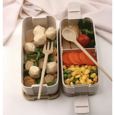 A bento box lunch with food items and cutlery.