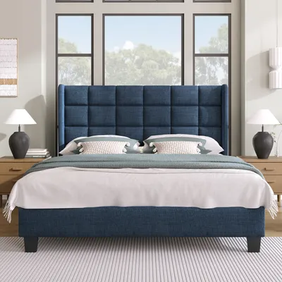 A bedroom scene with a blue upholstered bed as the main focus, set against a backdrop of large windows and subtle wall decor.