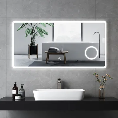 A modern bathroom with a large LED mirror reflecting a bathtub and a plant.