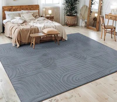 A bedroom scene with a bed, rug, and furniture.