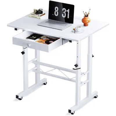A white adjustable height desk with a laptop, books, and art supplies on it.