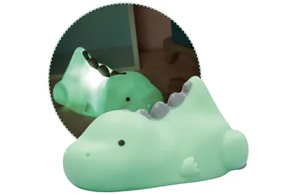 A mint green dinosaur-shaped night light is shown in front of a circular reflection of itself.