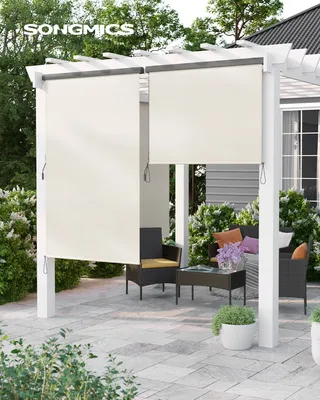 An outdoor patio with a pergola covered by beige roller shades, furnished with wicker chairs and a coffee table.