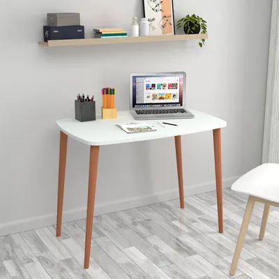 A white desk with a laptop, pens, and a notebook on it, set against a light gray wall and a light wood floor.
