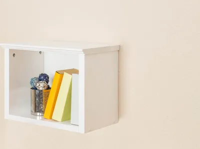 A white wall shelf with books and decorative balls.