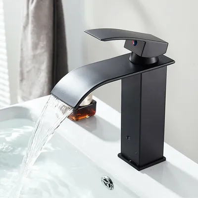 A black waterfall faucet is shown in use over a white sink, with water flowing.