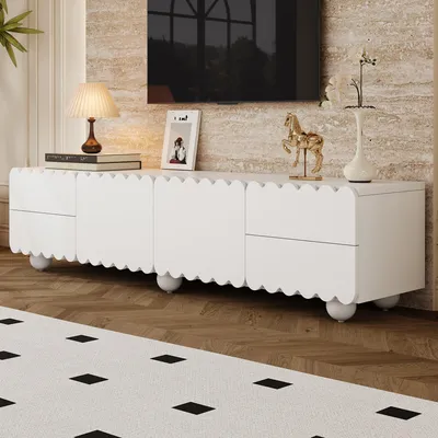 A white TV stand with scalloped edges and round legs is shown in a living room setting.