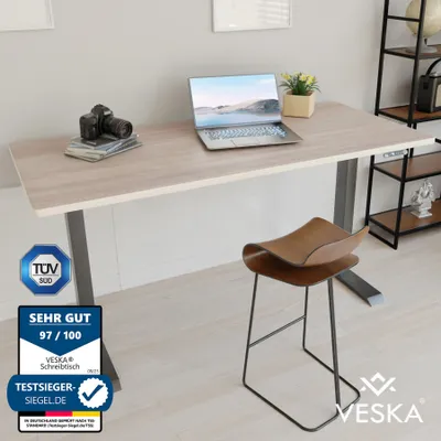 An office desk setup with a laptop, camera, and a stool.