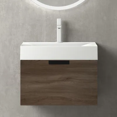 A modern bathroom vanity with a white sink and a wood-grain cabinet against a concrete wall.