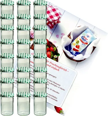 A collection of glass jars with green checkered lids, a packet of jelly powder, and some strawberries, arranged on a white surface with a recipe card.