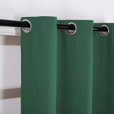 A close-up view of dark green curtains with grommets hanging from a black curtain rod.
