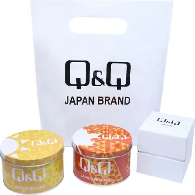 A Q&Q branded shopping bag with two decorative tins and a small white box.