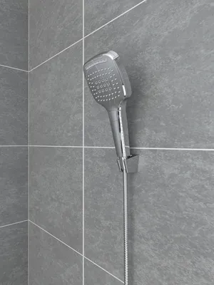 A chrome shower head mounted on a gray tiled wall.