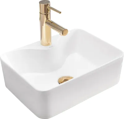 A white rectangular vessel sink with a gold faucet and drain.