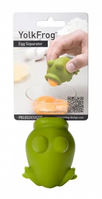 A hand is shown using a green frog-shaped egg separator to extract an egg yolk from a cracked egg into a glass bowl.