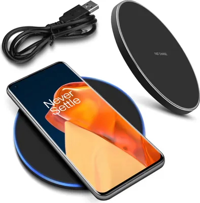 A smartphone is placed on a wireless charging pad, with a USB cable in the background.