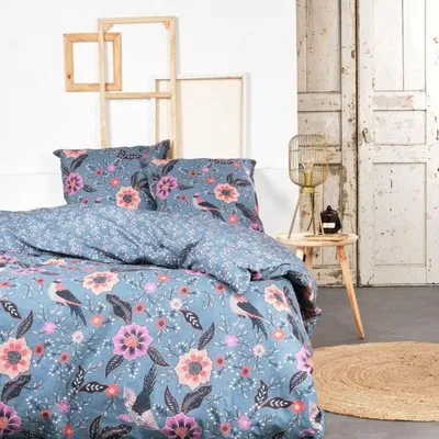 A bed with floral patterned bedding in a room with rustic decor.