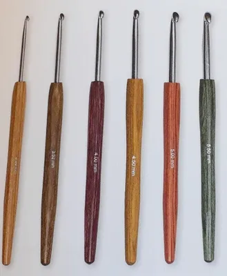 A set of six crochet hooks with wooden handles of different colors and sizes, laid out in a row against a white background.