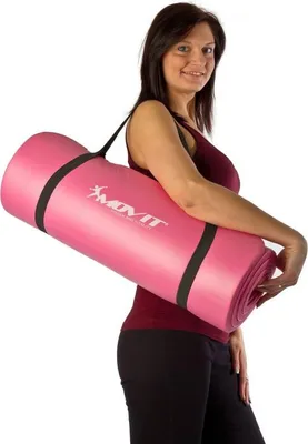 A woman is carrying a rolled-up pink yoga mat over her shoulder.