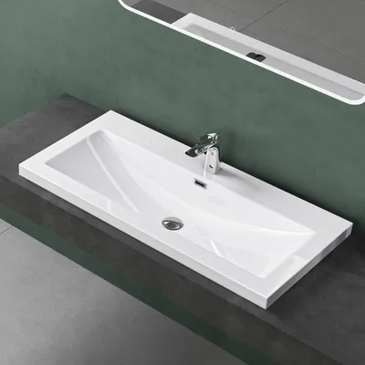 A white rectangular sink with a chrome faucet is shown on a dark gray countertop against a green wall.