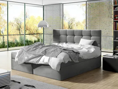A bedroom with a large window overlooking trees in autumn.
