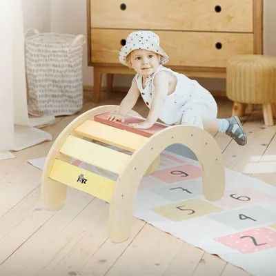 A baby is playing on a wooden climbing arch in a nursery.