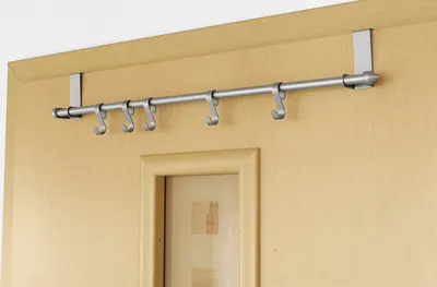 A metal door hanger with hooks is mounted on a wooden door.