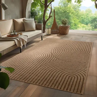 An outdoor patio with a sofa and a rug, surrounded by greenery.