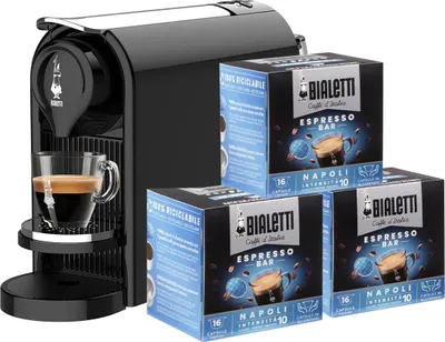 A black Bialetti espresso machine with three boxes of coffee capsules.