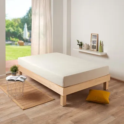 A bedroom scene with a bed, a small table, and a shelf on the wall.