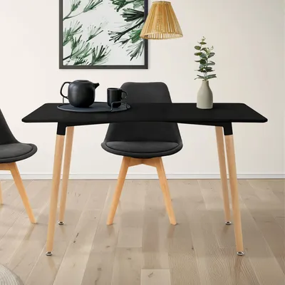 A dining table with chairs set up in a room, with a painting on the wall and a lamp overhead.