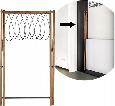 A wooden drying rack with black loops is shown next to a white wall and a dark doorway. An arrow indicates the rack is being moved into the doorway.