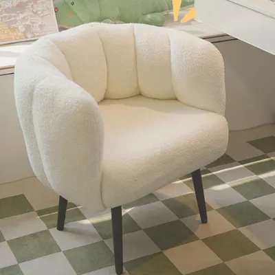 A white, fluffy armchair with a scalloped back is shown in a room with a checkered floor.