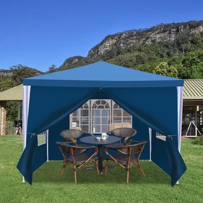 A blue gazebo set up on a grassy lawn in front of a house, with a mountain in the background.