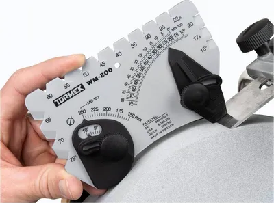 A hand holds a Tormek WM-200 angle gauge against a sharpening stone.