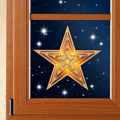 A wooden star decoration is placed in front of a starry night sky, viewed through a wooden window frame.