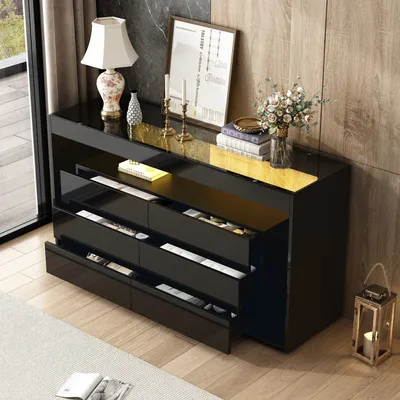 A modern black sideboard with drawers and an open shelf, decorated with a lamp, vase of flowers, and books, placed in a living room setting.
