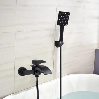 A black faucet and showerhead are mounted on a tiled wall above a bathtub filled with water.