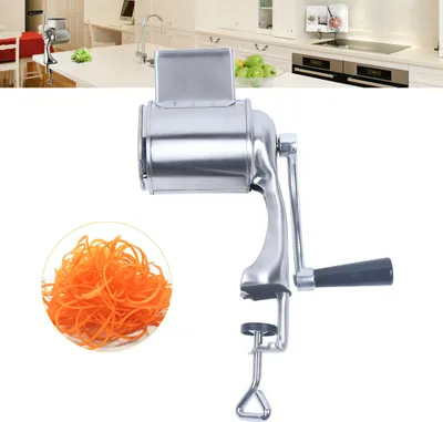 A stainless steel rotary grater with a clamp base, shown with a pile of shredded carrots.
