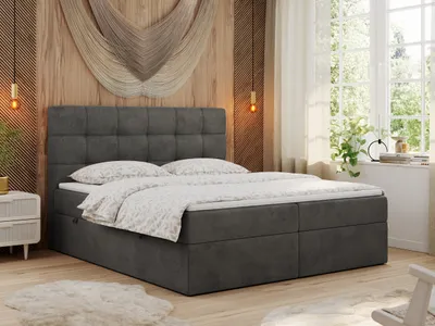 A bedroom scene with a bed as the main focus, decorated with a macrame wall hanging and plants.
