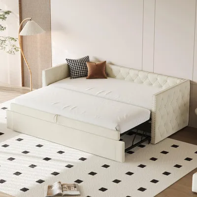 A cream-colored sofa bed is shown in a room with a floor lamp and a patterned rug.