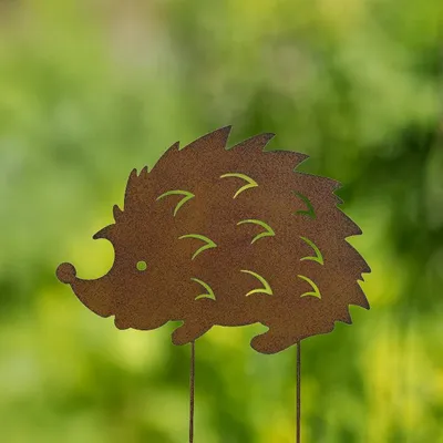 A metal garden stake shaped like a hedgehog against a blurred green background.