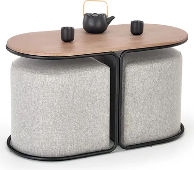 A coffee table with two ottomans, a teapot, and two cups on top.